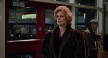 Movie still from “Working Girl” (1988), directed by Mike Nichols – A woman wearing a fur coat standing in front of a building; Medium shot, Low angle