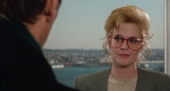 Movie still from “Working Girl” (1988), directed by Mike Nichols – A woman wearing a suit and glasses talking to a man wearing a suit; Close Up shot, Over the shoulder angle