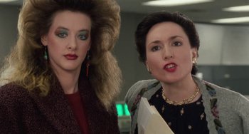 Movie still from “Working Girl” (1988), directed by Mike Nichols – Two women standing next to each other in front of a building; Close Up shot, Over the shoulder angle