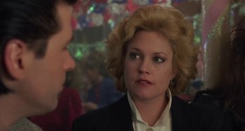 Movie still from “Working Girl” (1988), directed by Mike Nichols – A woman with blonde hair and a white shirt is talking to a man in a black suit; Close Up shot, Over the shoulder angle