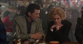 Movie still from “Working Girl” (1988), directed by Mike Nichols – A man and a woman sitting at a table in front of drinks; Medium shot, Over the shoulder angle