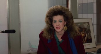 Movie still from “Working Girl” (1988), directed by Mike Nichols – A woman in a red coat with a big hair wig; Close Up shot, Over the shoulder angle