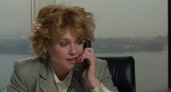 Movie still from “Working Girl” (1988), directed by Mike Nichols – A woman talking on a phone while sitting in a chair; Close Up shot, Low angle
