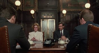 Movie still from “Working Girl” (1988), directed by Mike Nichols – A man and a woman sitting at a conference table; Medium shot, Over the shoulder angle