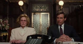 Movie still from “Working Girl” (1988), directed by Mike Nichols – A man and a woman sitting in front of a phone; Medium shot, Low angle