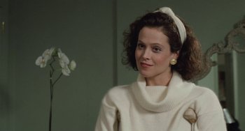 Movie still from “Working Girl” (1988), directed by Mike Nichols – A woman in a white sweater with a white bow in her hair; Close Up shot, Over the shoulder angle