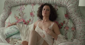 Movie still from “Working Girl” (1988), directed by Mike Nichols – A woman in white lingerie sitting on a couch; Medium shot, High angle