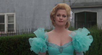 Movie still from “Working Girl” (1988), directed by Mike Nichols – A woman wearing a blue dress and a flower in her hair; Medium shot, Low angle