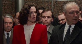 Movie still from “Working Girl” (1988), directed by Mike Nichols – A group of people standing next to each other in a building; Medium shot, Over the shoulder angle