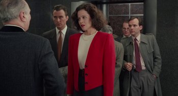 Movie still from “Working Girl” (1988), directed by Mike Nichols – A woman in a red jacket standing next to a group of men; Medium shot, Over the shoulder angle