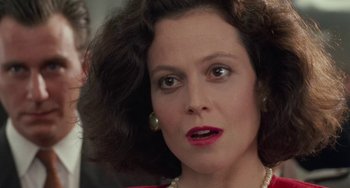 Movie still from “Working Girl” (1988), directed by Mike Nichols – A woman that is wearing pearls and a red dress; Close Up shot, Over the shoulder angle