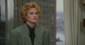 Movie still from “Working Girl” (1988), directed by Mike Nichols – A woman with blonde hair wearing a suit and black tie; Medium shot, Low angle