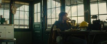 Movie still from “Wrong Turn” (2021), directed by Mike P. Nelson – A woman sitting at a table in front of a window; Medium shot, Low angle
