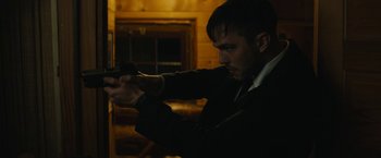 Movie still from “Wrong Turn” (2021), directed by Mike P. Nelson – A man in a suit and tie holding a gun; Medium shot, Over the shoulder angle