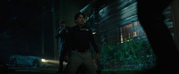 Movie still from “Wrong Turn” (2021), directed by Mike P. Nelson – A man in a black shirt is standing in front of a house; Medium shot, Over the shoulder angle