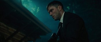 Movie still from “Wrong Turn” (2021), directed by Mike P. Nelson – A man wearing a suit and tie holding a camera; Close Up shot, Low angle