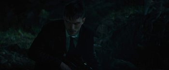 Movie still from “Wrong Turn” (2021), directed by Mike P. Nelson – A man in a suit and tie holding a gun; Medium shot, Over the shoulder angle