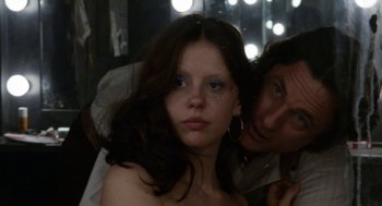 Movie still from “X” (2022), directed by Ti West – A young woman with a face full of makeup and a man with a face full of makeup; Close Up shot, Low angle