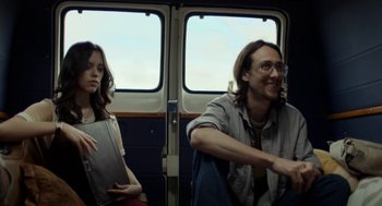 Movie still from “X” (2022), directed by Ti West – A man and a woman riding on a train; Medium shot, Low angle