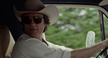 Movie still from “X” (2022), directed by Ti West – A man wearing a cowboy hat sitting in the driver's seat of a car; Close Up shot, Low angle