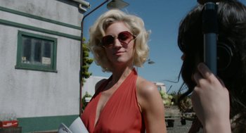 Movie still from “X” (2022), directed by Ti West – A woman in a red dress holding a newspaper; Close Up shot, Over the shoulder angle