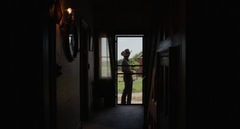 Movie still from “X” (2022), directed by Ti West – A man standing in front of an open door; Wide shot, Low angle