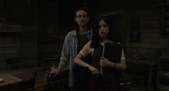 Movie still from “X” (2022), directed by Ti West – A man and a woman standing next to each other holding a laptop; Medium shot, Low angle
