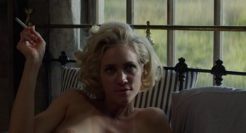 Movie still from “X” (2022), directed by Ti West – A woman sitting on a couch in front of a window; Close Up shot, High angle