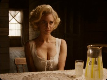 Movie still from “X” (2022), directed by Ti West – A woman sitting at a table with a glass of water; Medium shot, Over the shoulder angle