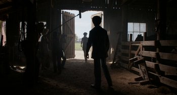 Movie still from “X” (2022), directed by Ti West – A group of people standing inside of a barn; Wide shot, Over the shoulder angle