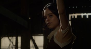 Movie still from “X” (2022), directed by Ti West – A young woman holding her arms up in the dark; Medium shot, Low angle