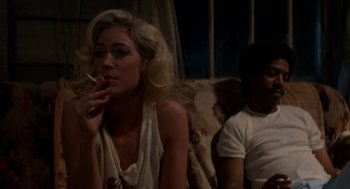 Movie still from “X” (2022), directed by Ti West – A woman sitting next to a man smoking a cigarette; Medium shot, Low angle