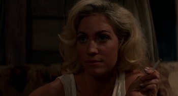 Movie still from “X” (2022), directed by Ti West – A woman with blonde hair and blue eyes looking at the camera; Close Up shot, Over the shoulder angle