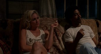 Movie still from “X” (2022), directed by Ti West – A woman sitting next to a man on a couch; Medium shot, Over the shoulder angle