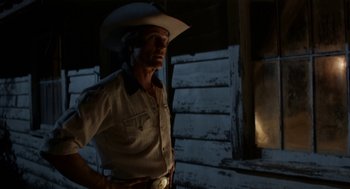 Movie still from “X” (2022), directed by Ti West – A man wearing a cowboy hat standing in front of a building; Medium shot, Low angle
