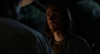 Movie still from “X” (2022), directed by Ti West – A man with long hair and glasses is looking at another man; Close Up shot, Over the shoulder angle