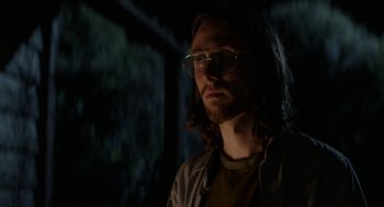 Movie still from “X” (2022), directed by Ti West – A man with long dark hair wearing glasses; Close Up shot, Low angle