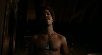 Movie still from “X” (2022), directed by Ti West – A shirtless man with a necklace in a dark room; Close Up shot, Low angle