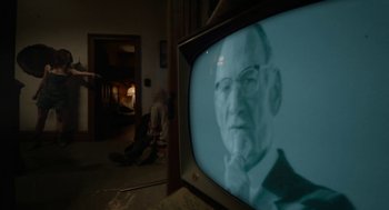 Movie still from “X” (2022), directed by Ti West – An old man is sitting on the floor in front of a television; Medium shot, Over the shoulder angle