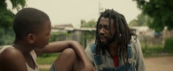 Movie still from “Yardie” (2018), directed by Idris Elba – A man with dreads talking to a woman; Close Up shot, Low angle