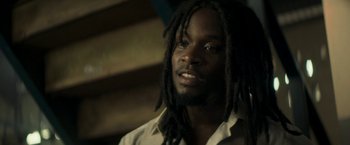Movie still from “Yardie” (2018), directed by Idris Elba – A person with dreads looking at the camera; Close Up shot, Low angle
