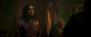 Movie still from “Yardie” (2018), directed by Idris Elba – A man with dreadlocks standing in front of a wall; Medium shot, Over the shoulder angle