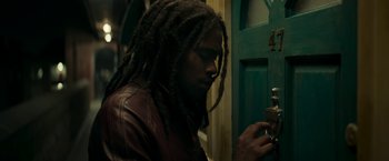 Movie still from “Yardie” (2018), directed by Idris Elba – A man with dreadlocks is looking at a lock; Close Up shot, Low angle