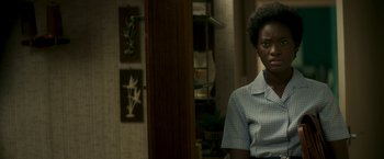 Movie still from “Yardie” (2018), directed by Idris Elba – A woman sitting in front of a mirror in a living room; Close Up shot, Over the shoulder angle