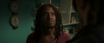 Movie still from “Yardie” (2018), directed by Idris Elba – A person with dreadlocks in a room; Close Up shot, Over the shoulder angle