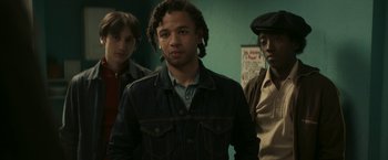 Movie still from “Yardie” (2018), directed by Idris Elba – A group of young men standing next to each other in a room; Medium shot, Low angle