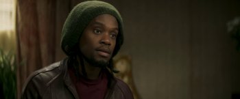 Movie still from “Yardie” (2018), directed by Idris Elba – A person wearing a jacket and a hat; Close Up shot, Over the shoulder angle