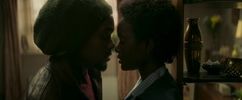 Movie still from “Yardie” (2018), directed by Idris Elba – A man and a woman are kissing in a room; Close Up shot, Low angle