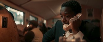 Movie still from “Yardie” (2018), directed by Idris Elba – A man is talking on a phone while sitting in a room; Close Up shot, Low angle