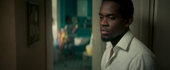 Movie still from “Yardie” (2018), directed by Idris Elba – A man with a beard is standing in a room; Close Up shot, Low angle